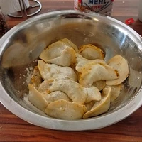 Foto einer metallischen Schüssel in der bemehlte ungekochte Pierogi liegen