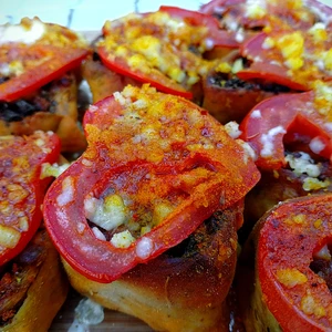 Pestoschnecken in Nahaufnahme, auf welchen Tomaten liegen und nachträglich mit veganen Feta überbacken wurden