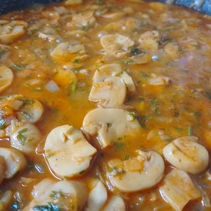 Nahaufnahme einer Pfanne mit den angebratenen Gemüse und Pilze, welche in einer Sauce schwimmen